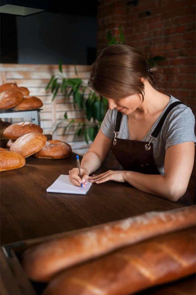 Panadera organizando documentos fiscales en su panadería en Madrid, apoyado por una gestoría especializada que ofrece soluciones contables y laborales.